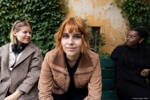 Three young women chatting on bench